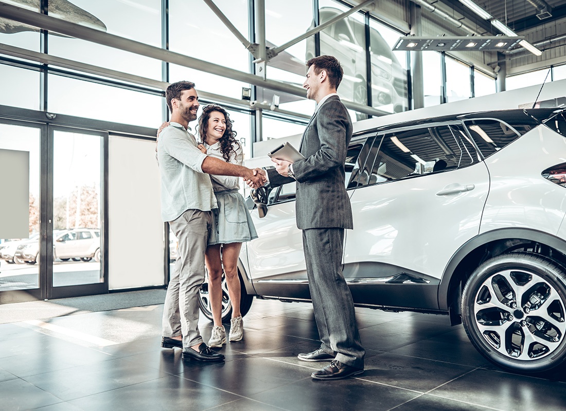 Business Insurance - Happy couple purchasing their first car at a dealership